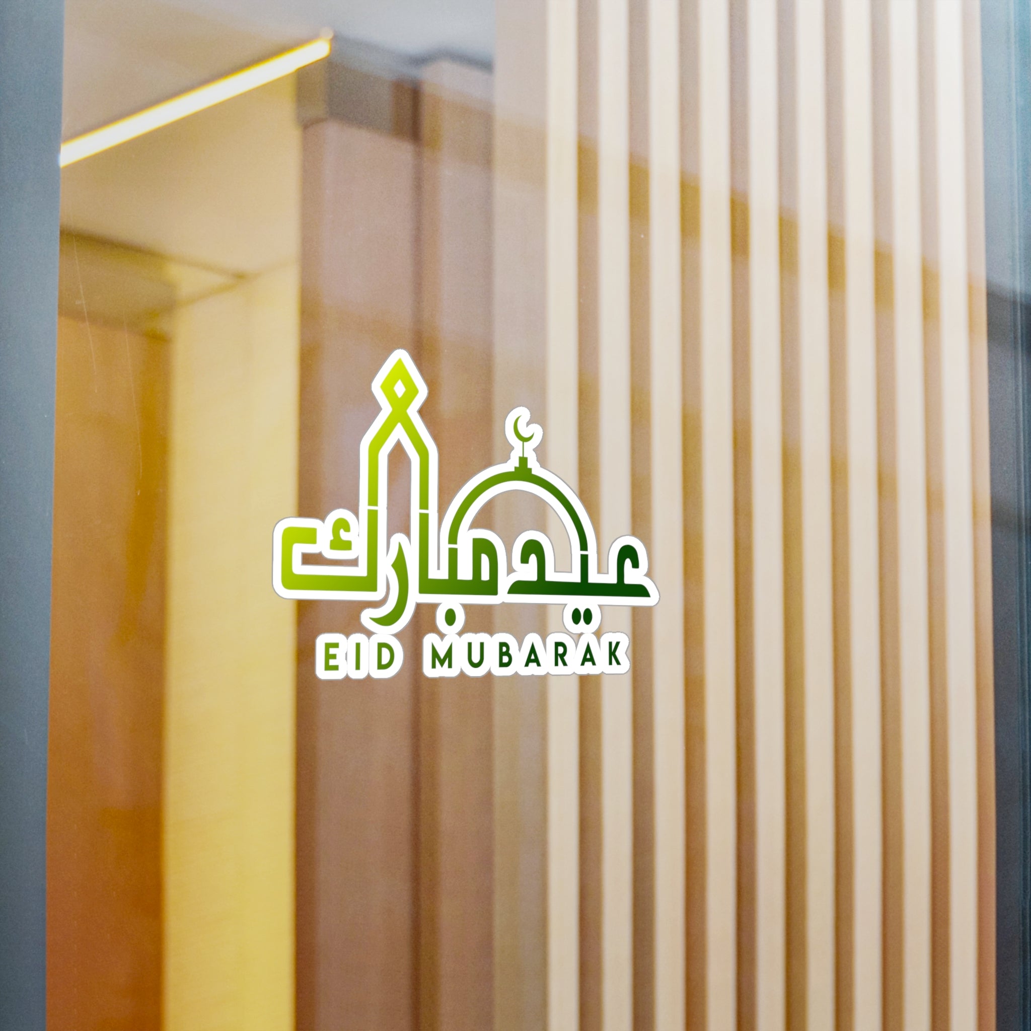 Eid Mubarak" transparent sticker from Medina Roots on a glass window with reflection and vertical blinds in the background, adding to the FestiveDecor.