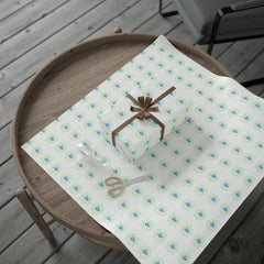 Gift-wrapped box with brown ribbon on a wooden table beside scissors and Medina Roots Eid Celebration Wrapping Paper - Ramadan Inspired Design for Meaningful Gifts for Eid.