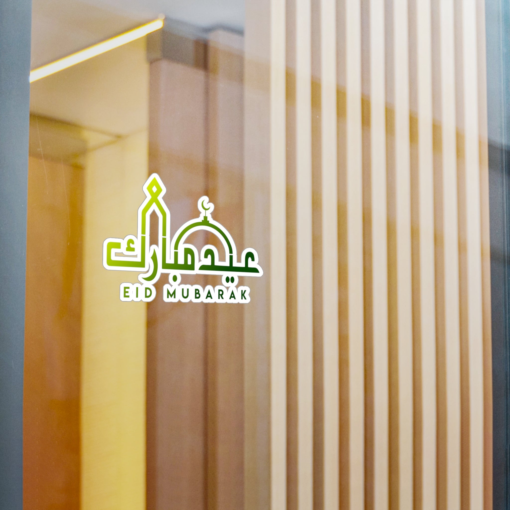 Eid Mubarak" transparent sticker from Medina Roots on a glass window with vertical blinds in the background.