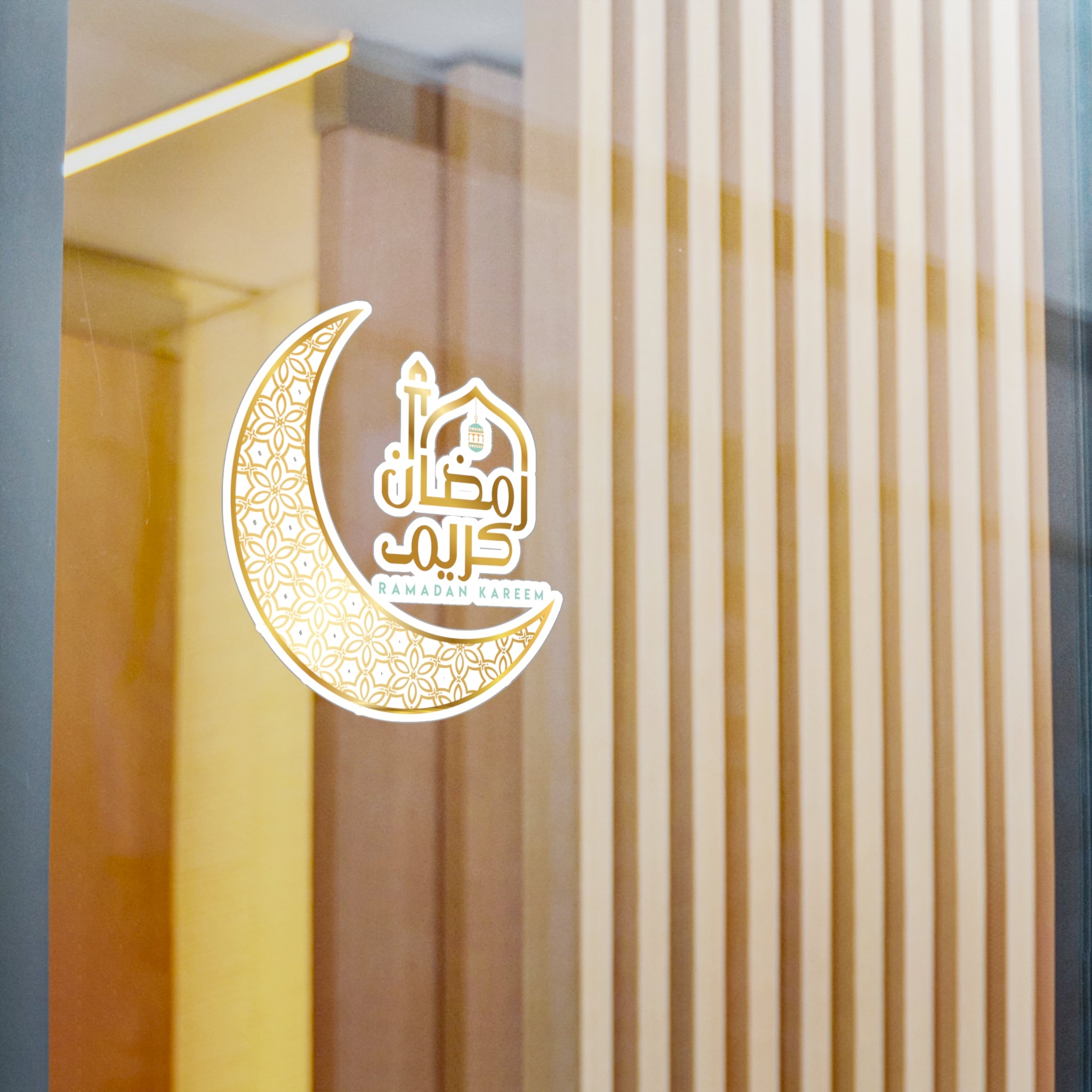 A Medina Roots Ramadan Kareem Transparent Outdoor Sticker on a glass window with vertical blinds in the background.