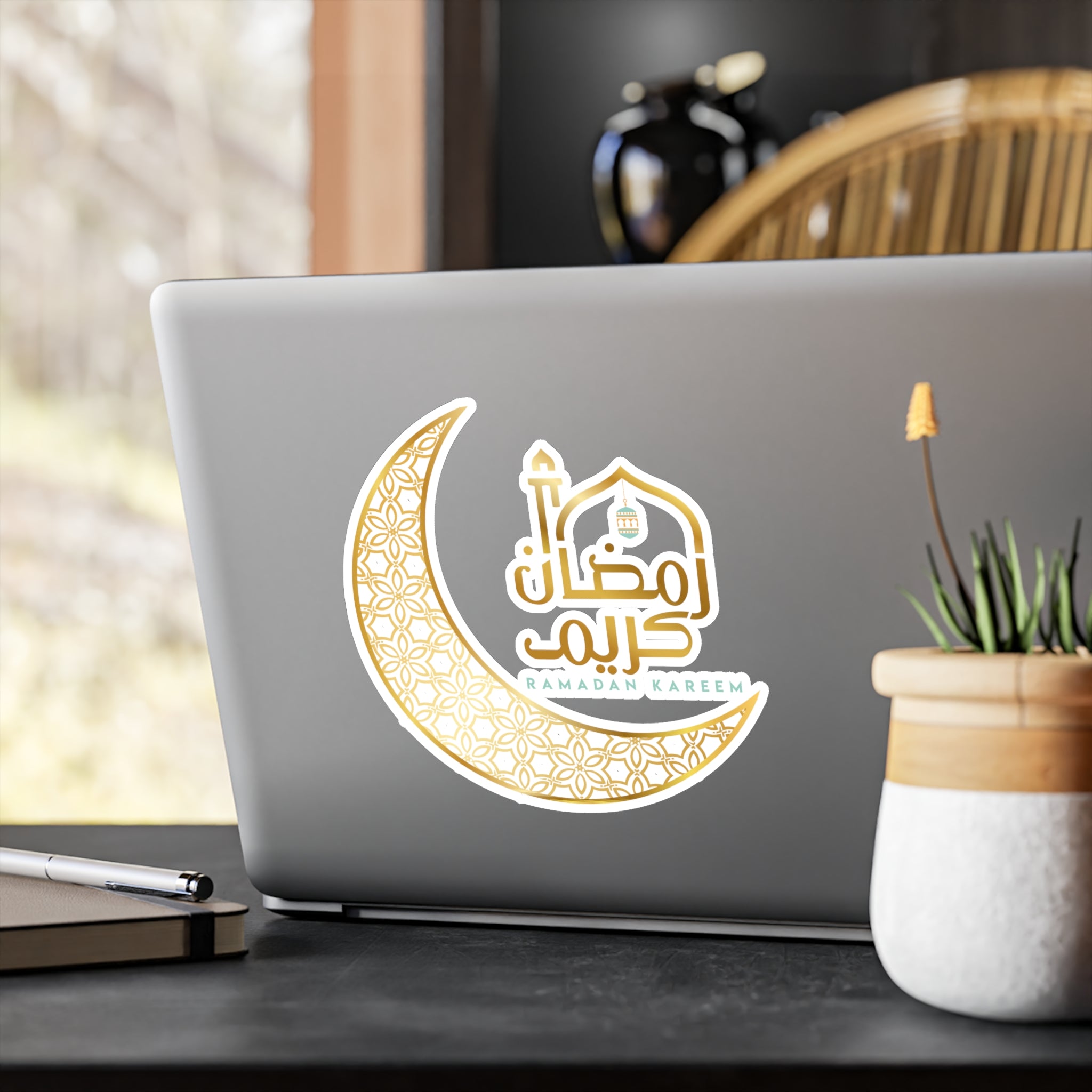 A laptop with Medina Roots Ramadan Kareem Transparent Outdoor Stickers, including a sticker depicting a crescent moon and a mosque.