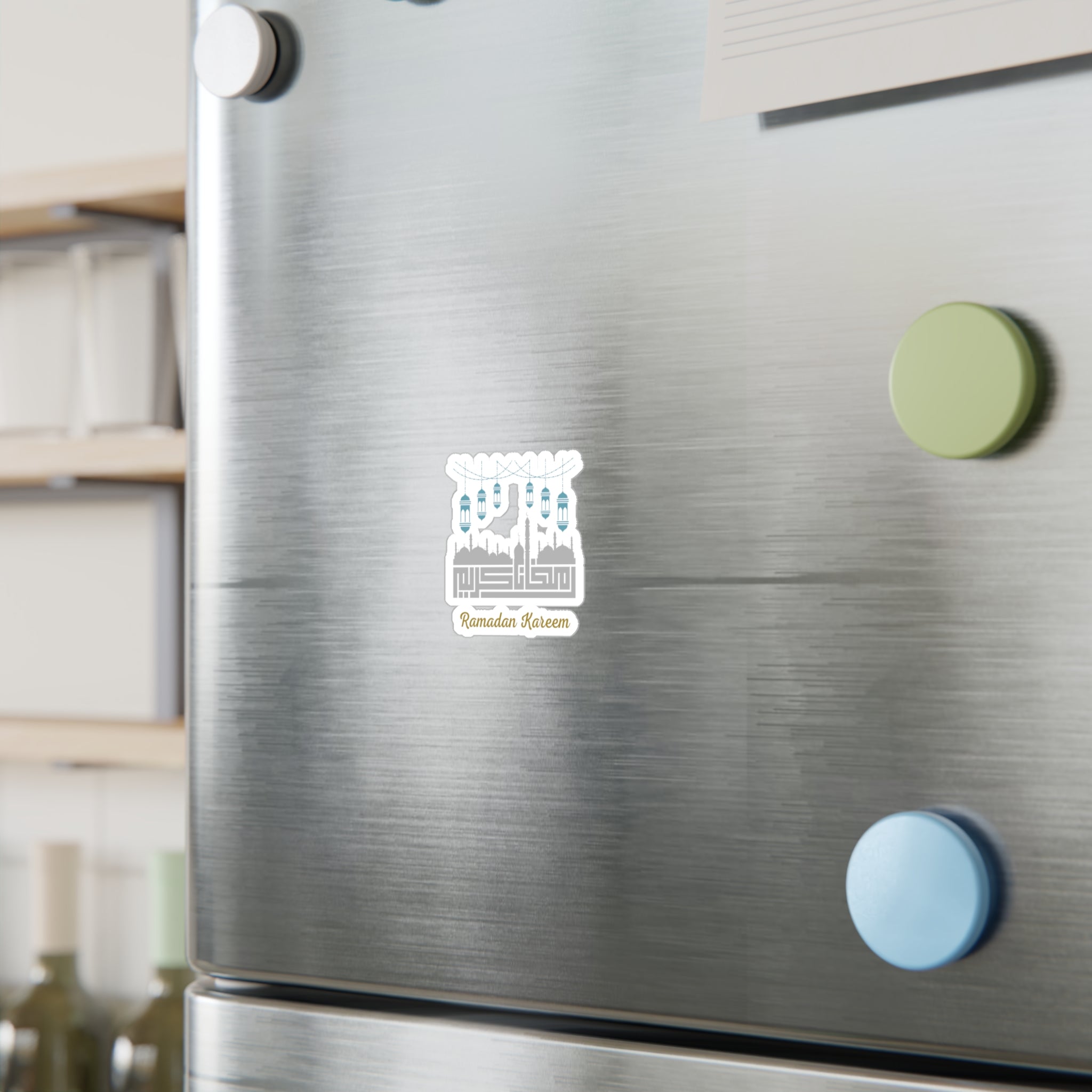 A stainless steel refrigerator door with a Ramadan Kareem Kiss-Cut Vinyl Decal from Medina Roots and colorful circular magnets.