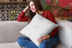 Woman sitting on a sofa, smiling and looking away, holding a Medina Roots Geometric Patterned Throw Pillow Cover with intricate geometric patterns.