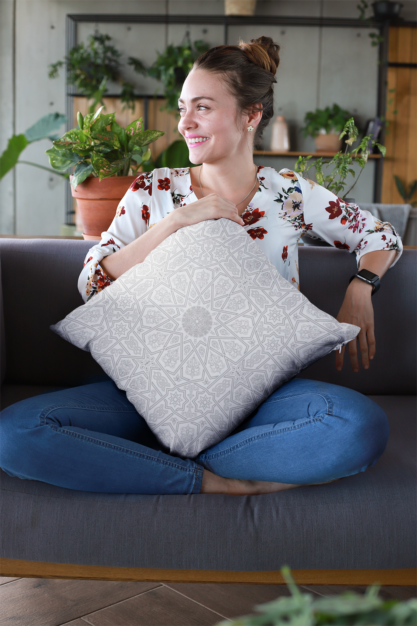 A smiling woman sitting cross-legged on a couch while holding a Medina Roots Geometric Patterned Throw Pillow Cover.