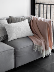 A cozy corner of a gray sofa adorned with a Medina Roots Geometric Patterned Throw Pillow Cover and a draped terracotta throw blanket.